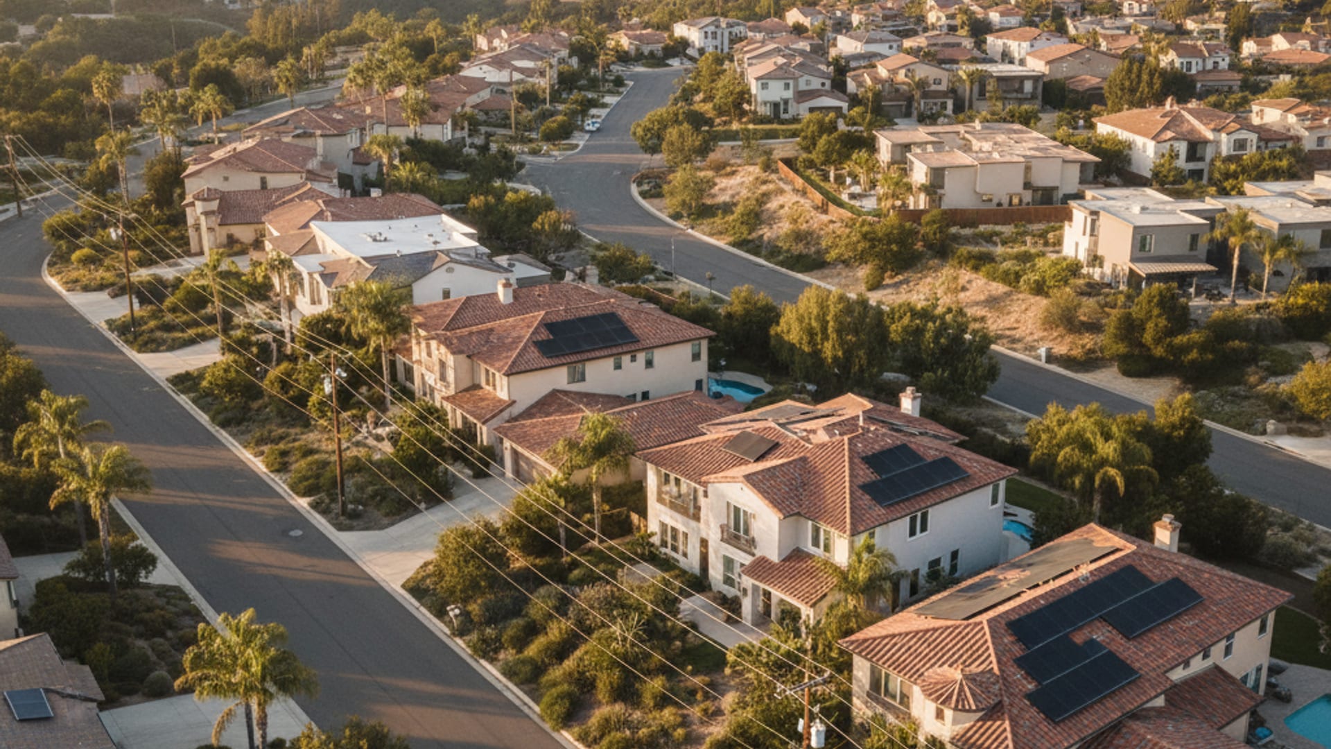 Aerial view of a San Diego County residential neighborhood with stucco homes and rooftop solar panels at golden hour